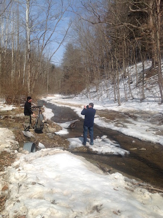 Photographer shoots Artist Painting Winter Stream in the Woods